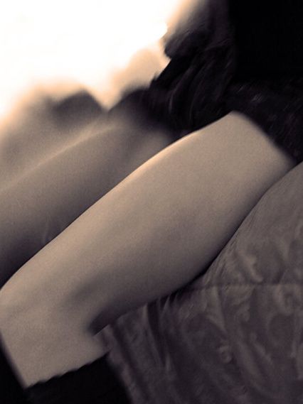 A bent leg and knee in soft light against dark fabric.