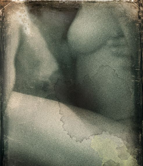 The curve of a nude body in soft grey-green, its edges stained like an aged photograph.