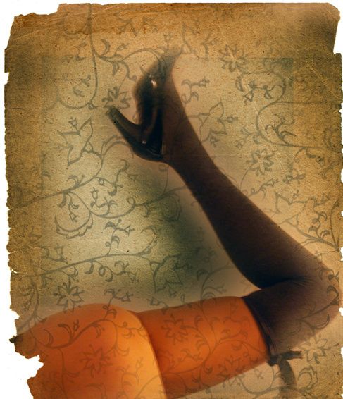 A leg in a black stocking and heel raised over an orange skirt, on patterned paper with torn edges.
