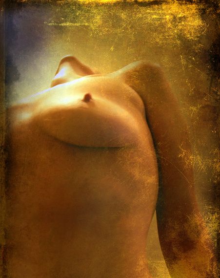 A nude torso lit in warm amber and gold, head turned away.