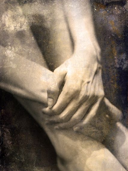 Hands clasped over crossed legs in grainy sepia.