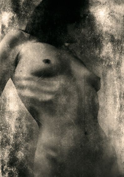 A nude torso emerging from dark, cracked texture.