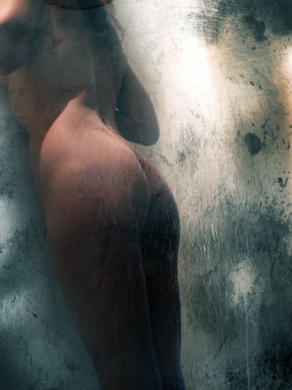 A body in shadow, seen in profile against a pale blue-green haze.