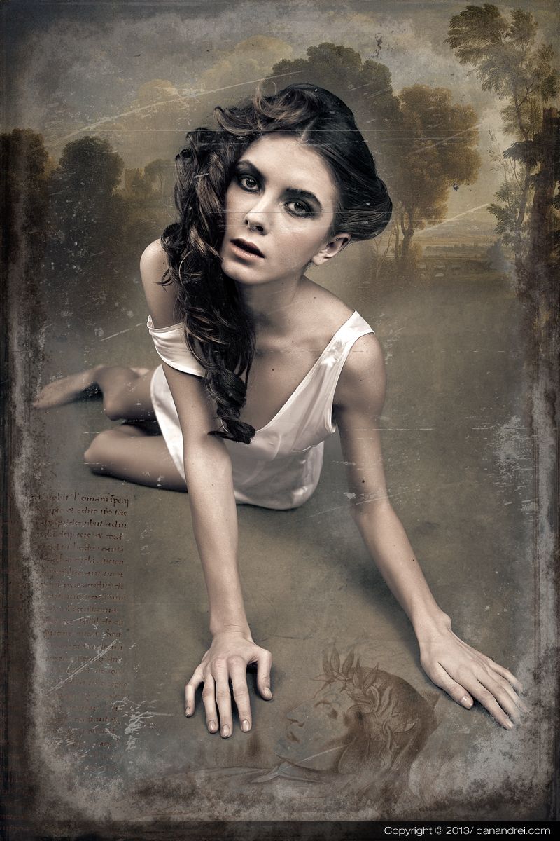 A young woman in a white slip sitting on the ground, leaning forward, before a faded landscape.