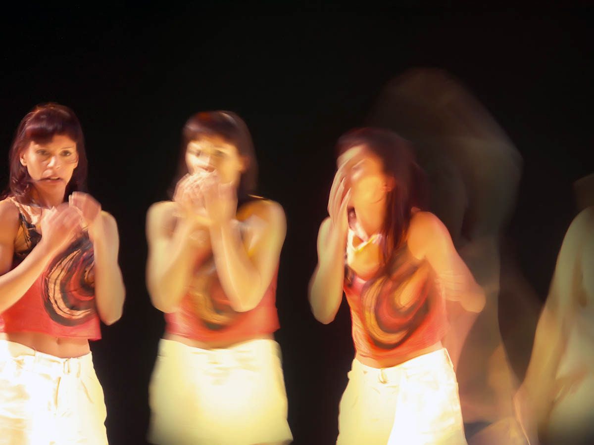 Three women in red tops repeating the same gesture, hands to their faces.