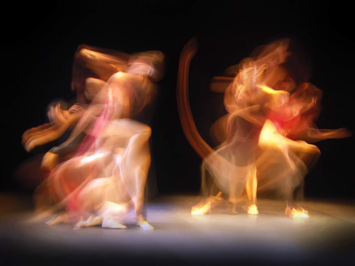 Two groups of dancers dissolving into swirls of orange and pink light.