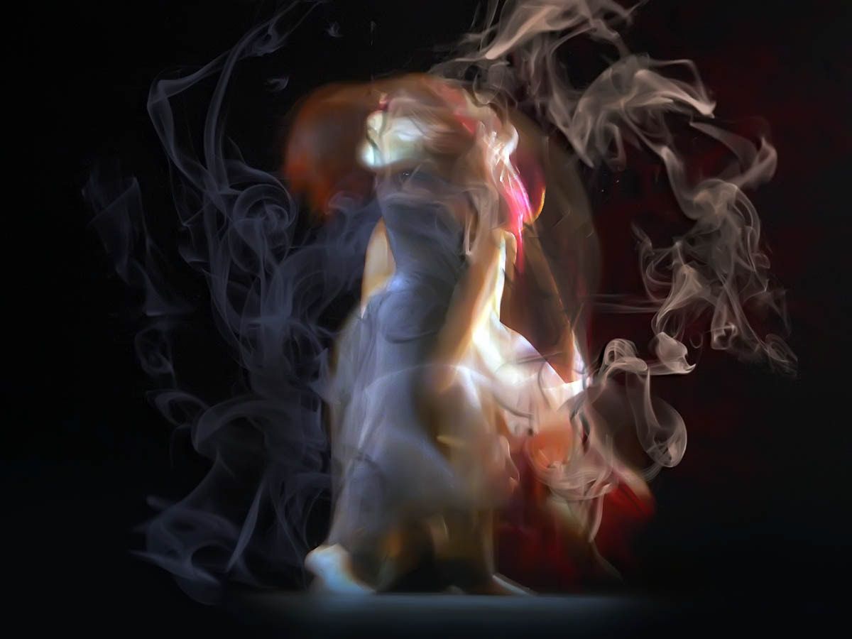 A single dancer wrapped in swirling smoke-like trails of pale blue and white.