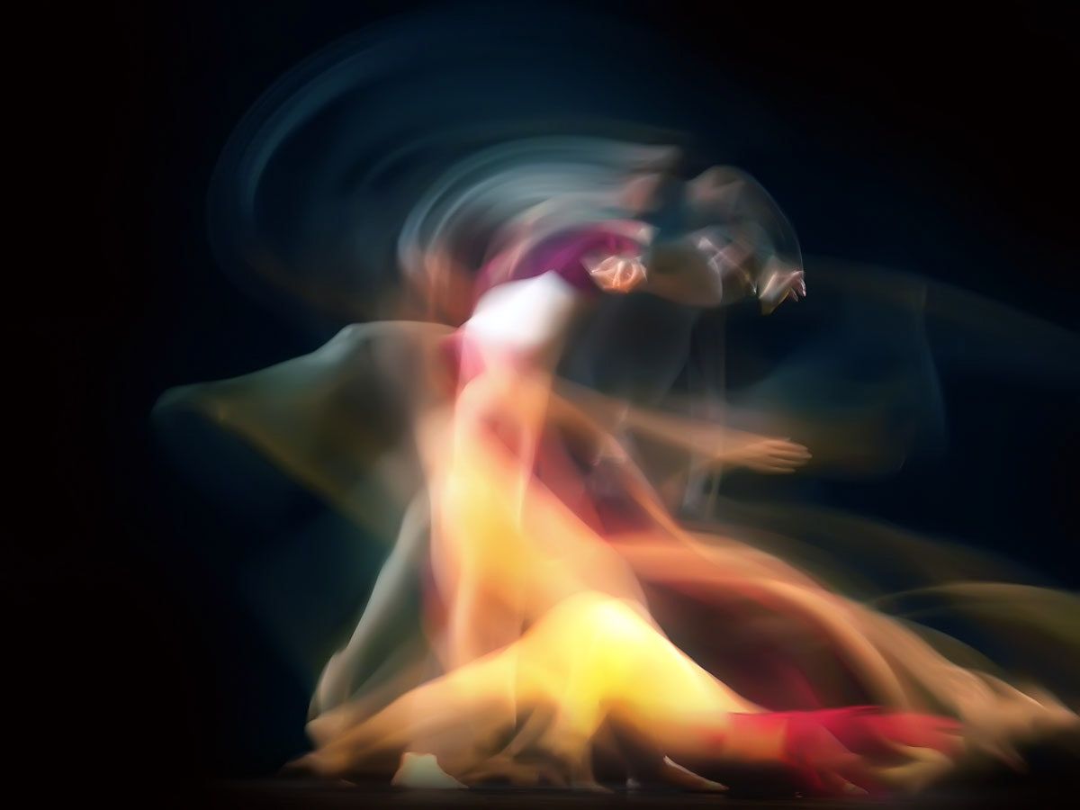 A dancer spinning in a vortex of pale blue and gold light.