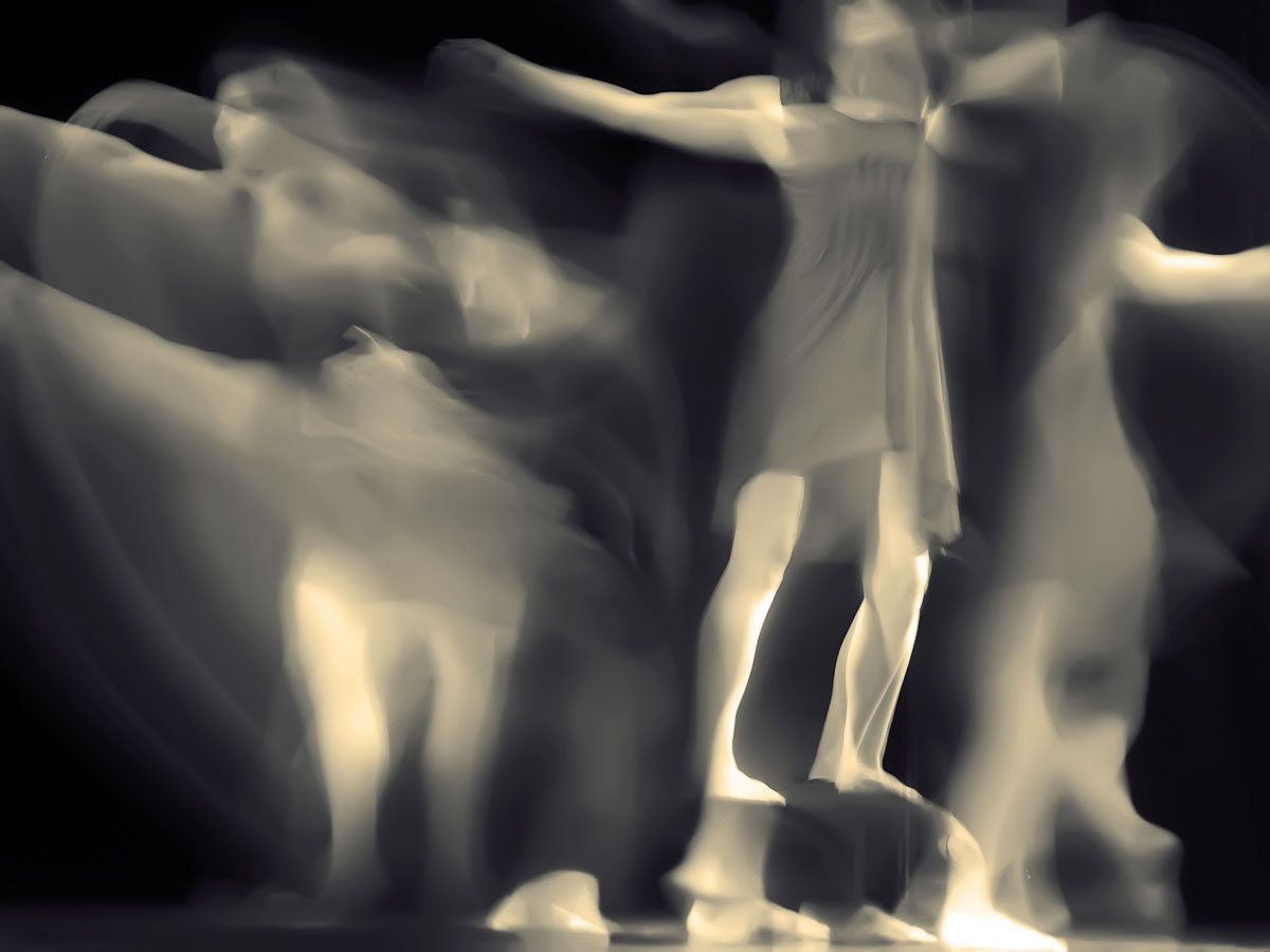 Dancers in pale cream tones, arms outstretched, dissolving in motion.