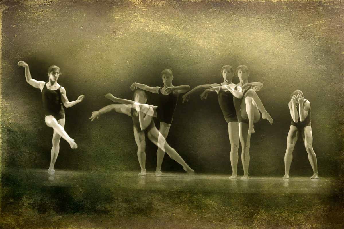 Four dancers in a line on a misty olive-toned stage, arms extended.