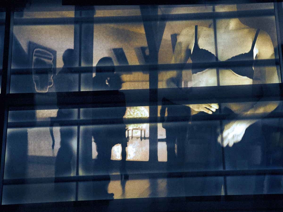 Silhouettes behind a grid of blue window frames and light.
