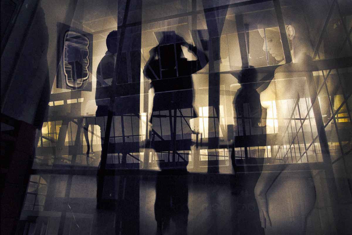 Silhouettes of visitors in a gallery, layered with window bars and reflections.