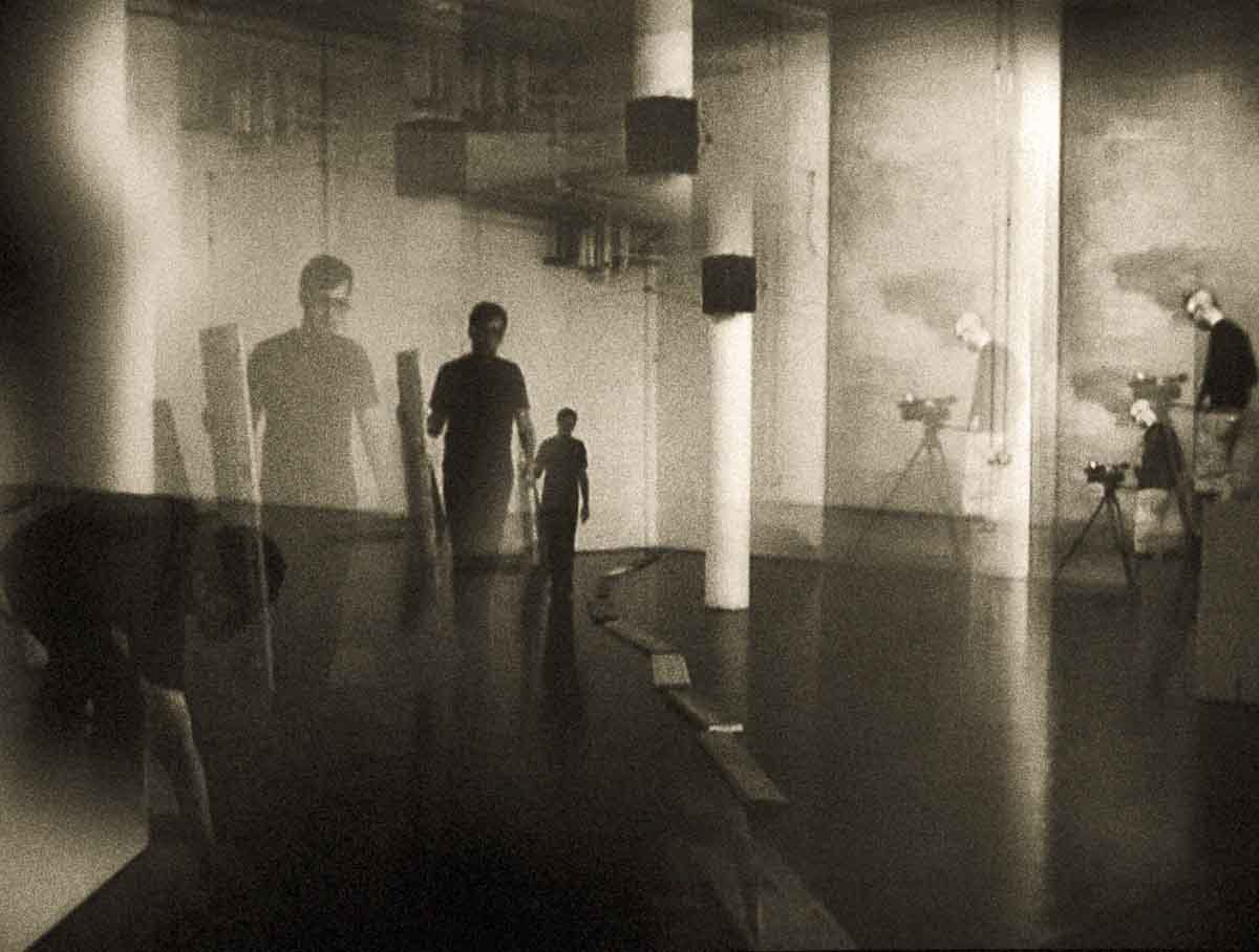 Figures and cameras in a large pale hall with columns.